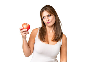 Middle age woman with an apple over isolated background with sad expression