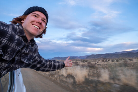 South Africa, Western Cape Province, Young Man Leaning Out Of Window Of Moving Car