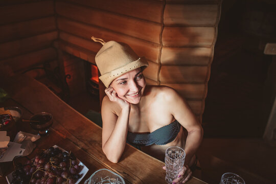 Smiling woman with hat day dreaming in sauna