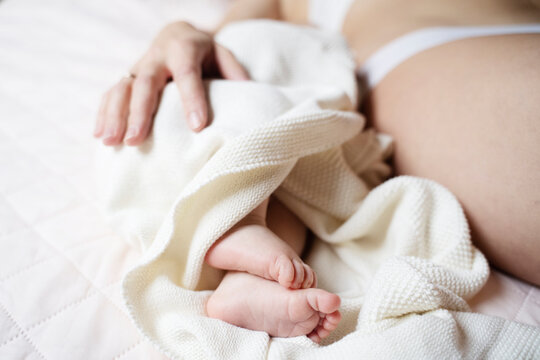 Baby boy lying by mother on bed