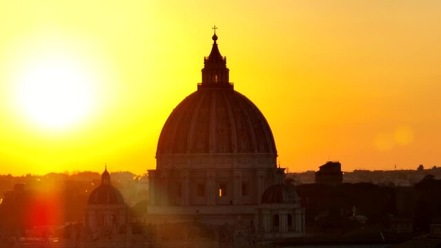 Tramonto sulla cupola di San Pietro a Roma.
Vista aerea, primopiano controluce della Basilica illuminata dal sole giallo
