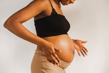 Woman with pregnant belly standing in front of white wall