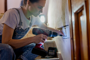 Young woman doing wall repair at home using drill screwdriver
