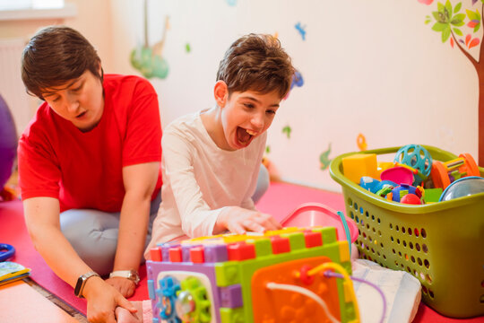 Happy Physical Therapist And Girl With Disability Playing At Rehabilitation Centre