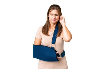 Middle age with broken arm and wearing a sling over isolated background frustrated and covering ears