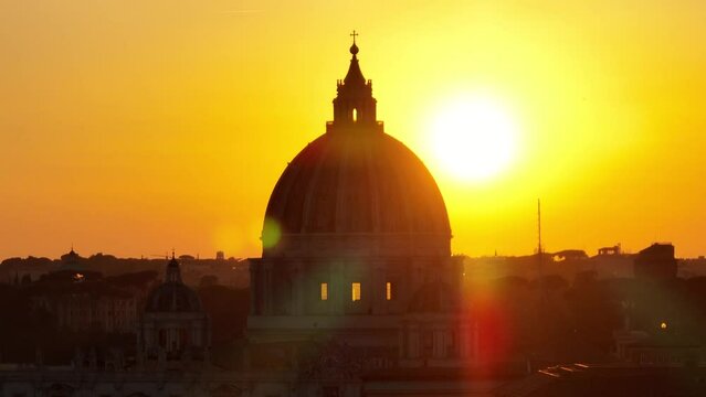 Tramonto sulla cupola di San Pietro a Roma.
Vista aerea, primopiano controluce della Basilica illuminata dal sole giallo
