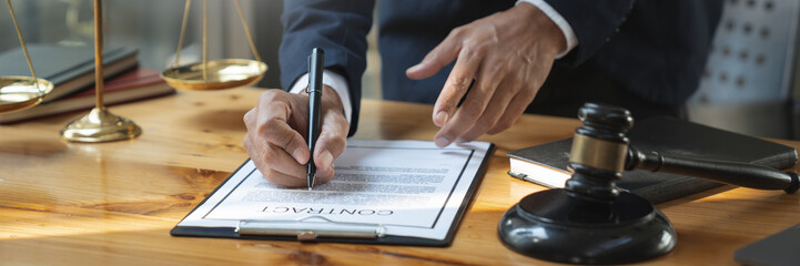 Young Asian lawyer or legal advisor reading clarification on business agreement with the signing of the investment contract according to the laws and regulations in the office.