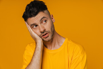 Young white man propping his head with hand and looking aside