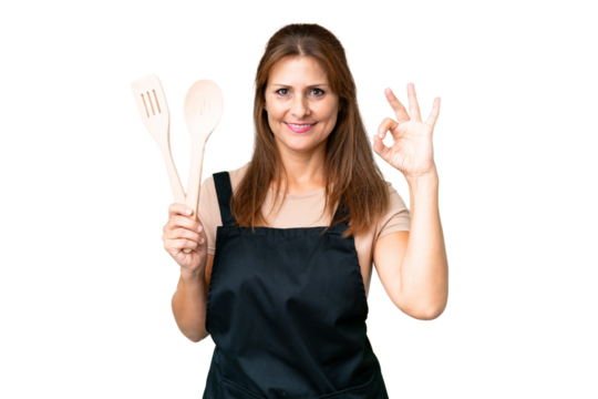 Middle age caucasian woman holding a rolling pin over isolated background showing ok sign with fingers