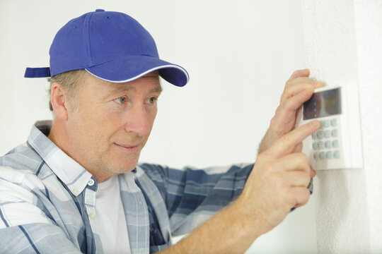 mature male worker installing alarm system