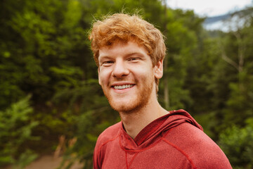 Young white bearded man smiling while walking in forest