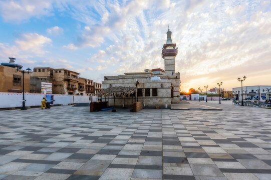 Building in town square under cloudy sky at sunset
