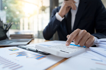 Asian businessman working in the office, calculating financial reports, organizing paperwork using a laptop and calculator as an aid.management concept accounting.