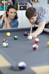 happy couple playing billiards on vacation together
