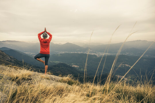 Mature woman practicing tree pose yoga on mountain