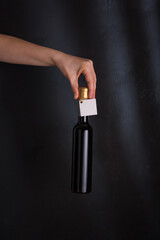 hand holding 250 ml bottle of red wine with mock up label, no brand on black background. Cabernet...