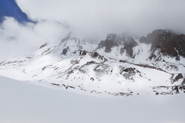 Fototapeta na wymiar Mountains in snow and fog, alpine peaks
