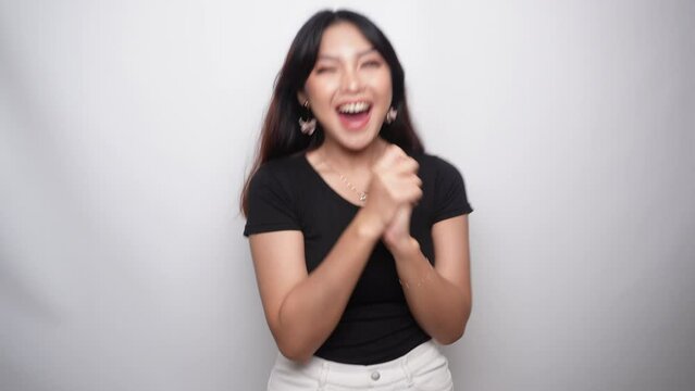 Happy excited and smiling young Asian woman raising his arm up to celebrate success or achievement. Indonesian women wearing black shirt