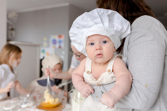 Mother holding cute boy with chef's hat at home