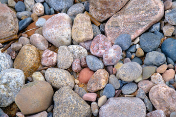 Background of sea stones. Stones of different shapes, sizes and colors on the seashore, close-up.