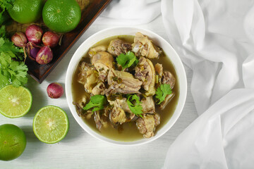 Homemade chicken soup with galangal,  lemon grass in white bowl.