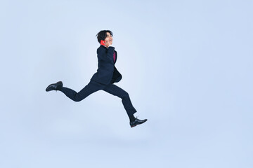 Fototapeta na wymiar スマホで通話しながらジャンプする若いビジネスマン