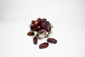photo a small bowl of dates next to a handful on white background. high quality photo