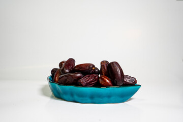 photo a small bowl of dates next to a handful on white background. high quality photo