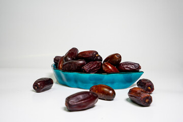 photo a small bowl of dates next to a handful on white background. high quality photo