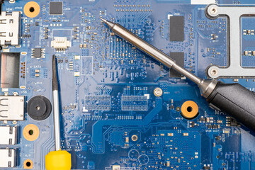 Soldering iron and screwdriver on the surface of the printed circuit board with chips as a concept of electrical work