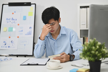 Stressed businessman touching his head suffering from headache, exhausted from overwork or stress at work