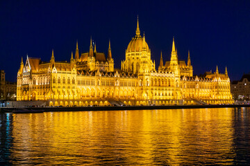 Fototapeta premium The Budapest Parliament building at night, with the Danube in the foreground