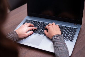Photo of hands of young woman typing on her laptop