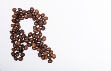R is a capital letter of the English alphabet made up of natural roasted coffee beans that lie on a white background.