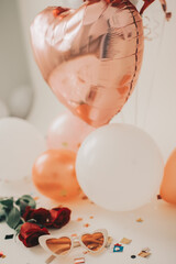 Heart sunglasses next to confetti, roses and balloons for holiday