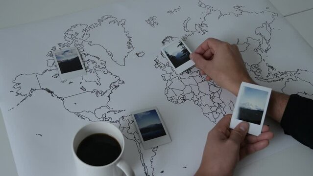 Stock Video Clip of Person Hands Sorting Polaroid Photos on World Map