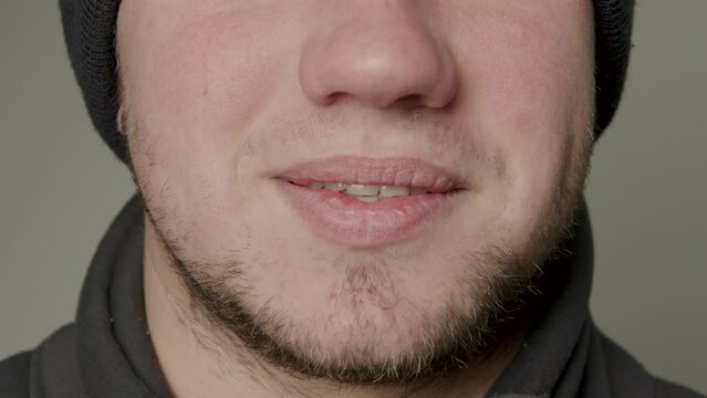 Close-up beauty portrait of a young man with smooth, healthy skin, natural lips, modestly smiling. Natural and healthy smile of a young man. Straight and healthy teeth. Dental concept