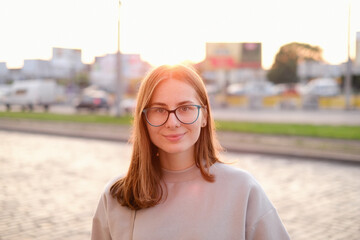 Portrait of a young woman in glasses walking through the evening city