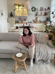 Young girl drinks coffee and holding smartphone sitting on a couch