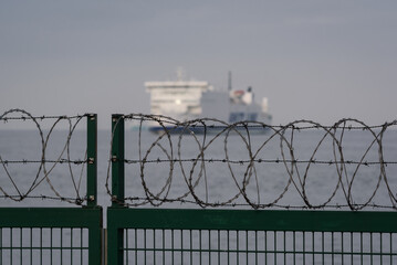 PROTECTING SITE - Separating seaport with fence and razor wire 
