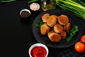 fried chicken nuggets on a black plate, ketchup in a saucepan, v