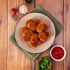 chicken nuggets on a plate with sauce, wooden countertop