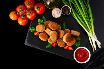 fried chicken nuggets on a black plate, ketchup in a saucepan, v