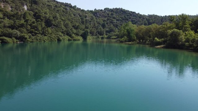 Immerse in the serenity of a tranquil lake in Epirus, surrounded by lush greenery.  Still waters of the lake reflect the beauty of the surrounding landscape, creating a peaceful scene | 4K