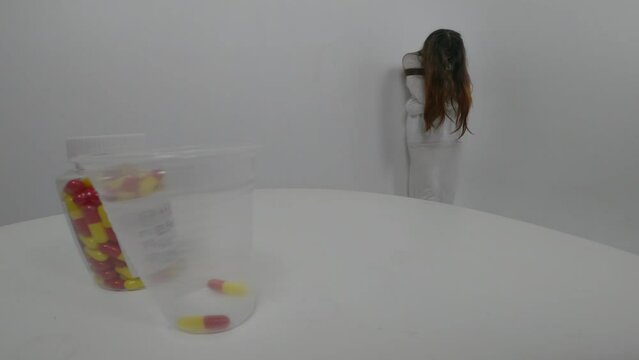 Point of view  hands of male doctor giving pills to female patient in  straitjacket. Treatment of schizophrenia in psychiatric clinic. Pills on the table