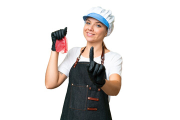 Butcher woman wearing an apron and serving fresh cut meat over isolated chroma key background showing and lifting a finger