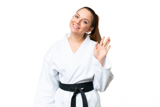 Young blonde woman doing karate over isolated chroma key background saluting with hand with happy expression