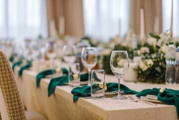 Wedding set up, dinner table reception. Flower composition with eucalyptus leaves in the center of the table and burning candles.