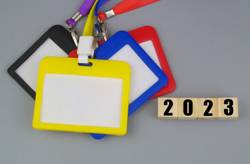 Colorful blank badges with strings and numbers 2023 on wooden cubes. Access for events in 2023 concept.	