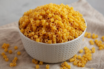 Raw Ditalini Pasta in a Bowl on a gray background, low angle view.